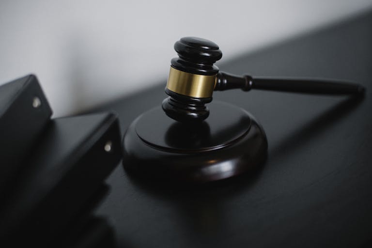 Marteau de juriste en bois sur un bureau qui symbolise l'authorité et la loi.